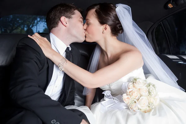 Nygift par kyssas i limousine — Stockfoto