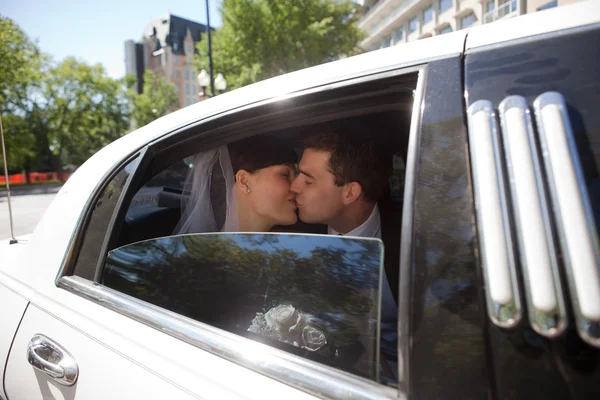 Brautpaar küsst sich in Limousine — Stockfoto