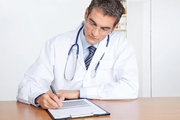 Doctor masculino escribiendo en portapapeles — Foto de Stock