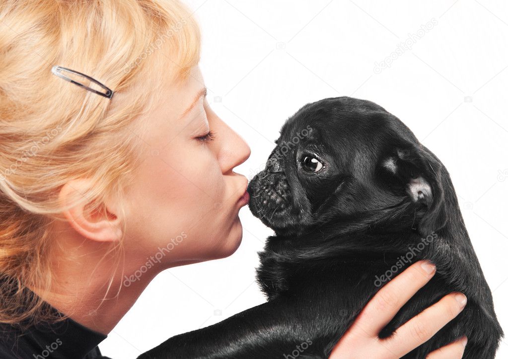 Cute blonde kissing a black pug puppy