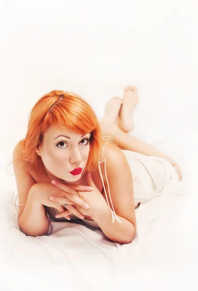 Redhead pinup girl posing on a bed — Stock Photo, Image