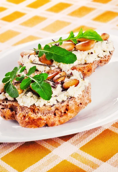 Open faced sandwices with goat cheese, almonds and arugula — Stock Photo, Image