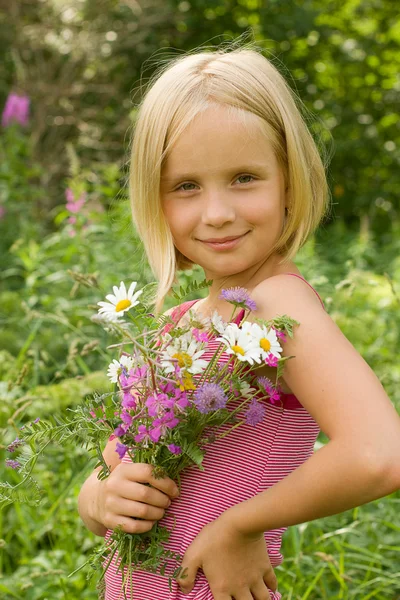 Menina sorridente bonita com flores de prado ao ar livre — Fotografia de Stock