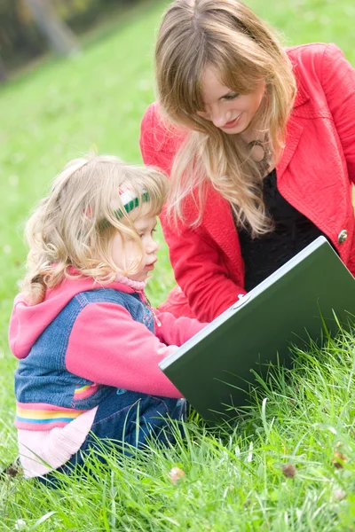 Mamá e hija pequeña con portátil al aire libre —  Fotos de Stock