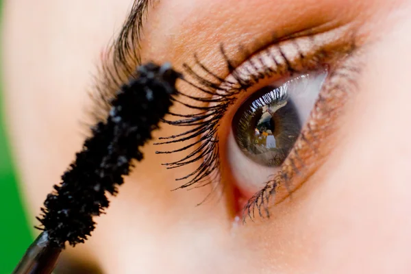 Schöne Frau, die Wimperntusche mit Pinsel auf ihr Auge aufträgt — Stockfoto
