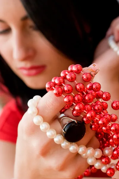 Morena bonita segurando contas vermelhas e brancas na mão — Fotografia de Stock