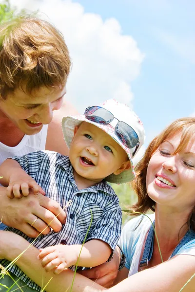 Familia feliz con hijo sobre fondo azul cielo — Foto de Stock