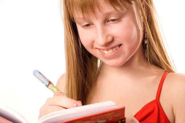 Όμορφο έφηβο κορίτσι χαμογελά, καταγράφοντας σε απομονωμένες o σημειωματάριο — Φωτογραφία Αρχείου