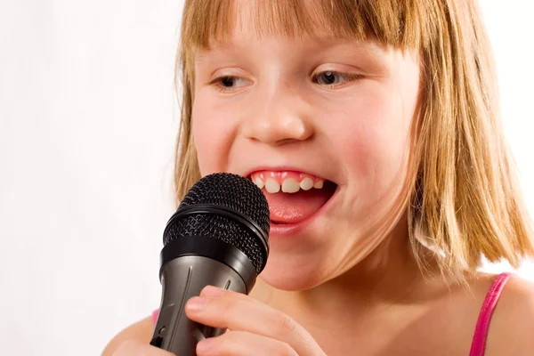 Hübsche kleine Mädchen singen in Mikrofon isoliert über weiß — Stockfoto