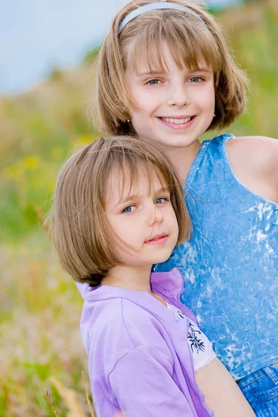 Joyeuses petites sœurs sur fond de prairie verte — Photo