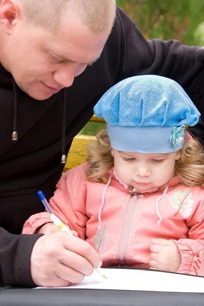 Батько навчає маленьку доньку писати Ліцензійні Стокові Зображення