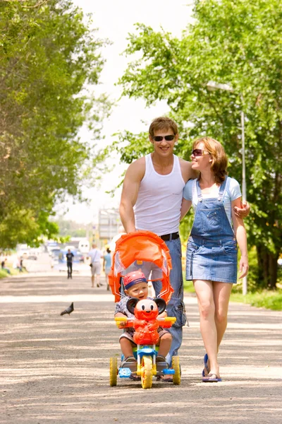 Rodina s dítětem v kočárku pěšky přes městský park Royalty Free Stock Fotografie