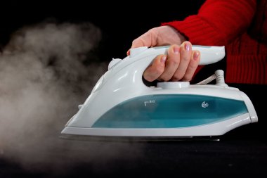 Hand in red sleeve holding steaming iron