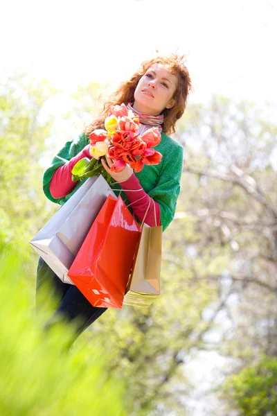 Beautiful woman with shopping bags and tulips — Stock Photo, Image