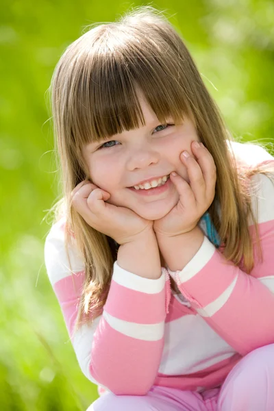 Liten flicka klädd i rosa blus på gröna sommaren gräs — Stockfoto