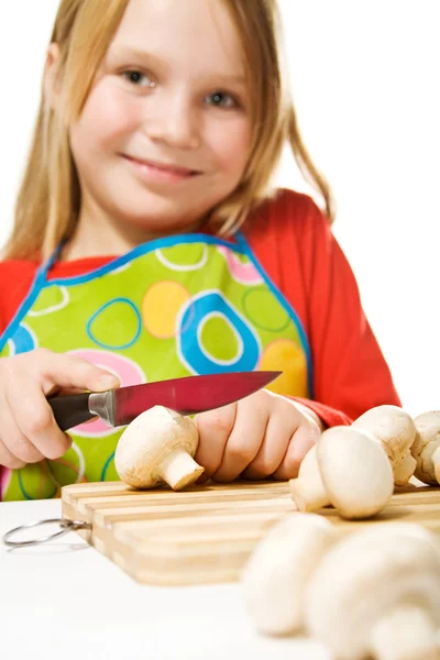 Девочка в фартуке, нарезает грибы. — стоковое фото