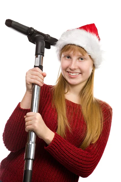 微笑着十几岁的女孩在用真空吸尘器扫帚圣诞老人帽子 — 图库照片