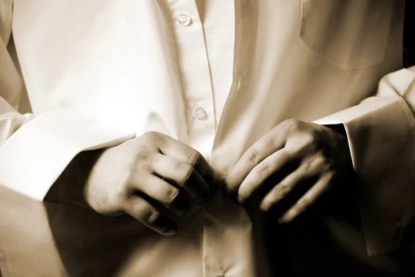 Человек крепления кнопки на белой рубашке — стоковое фото