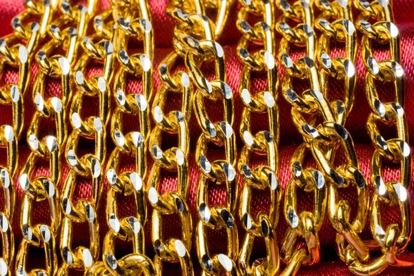 Cadena de color dorado sobre seda roja —  Fotos de Stock