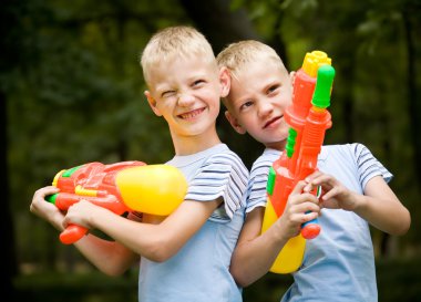 Two smiling twin brothers with water guns clipart