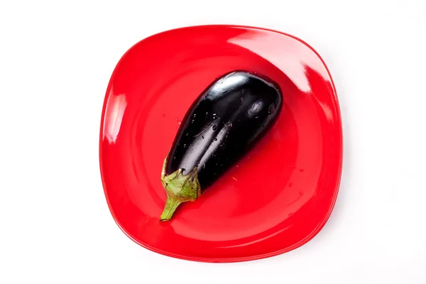 Kırmızı plaka üzerinde mavi patlıcan — Stok fotoğraf