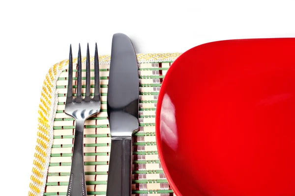 Plaque rouge, couteau et fourchette isolés sur blanc — Photo