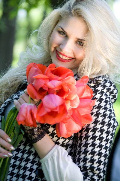 Blondine mit roten Tulpen — Stockfoto