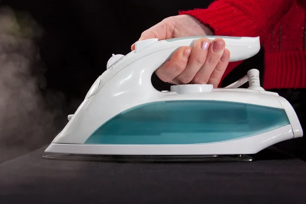 stock image Hand in red sleeve holding steaming iron