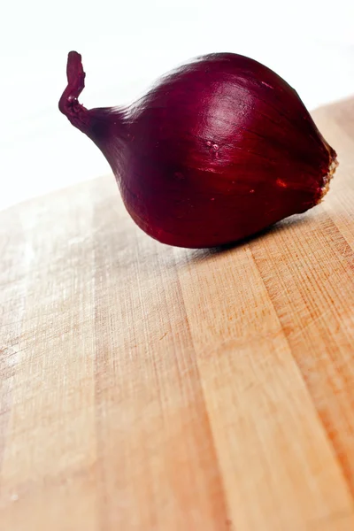 Ολόκληρα κόκκινα κρεμμύδι σε σανίδα — Φωτογραφία Αρχείου