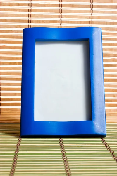 Blauwe houten frame op bamboe mat — Stockfoto