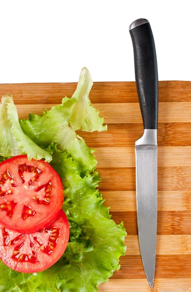 Tranches de tomate rouge, feuilles de salade et un couteau — Photo