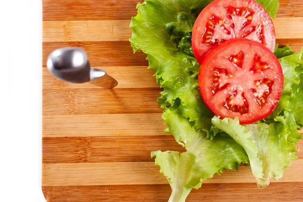 Plastry pomidora czerwone, liście sałaty i nóż — Zdjęcie stockowe