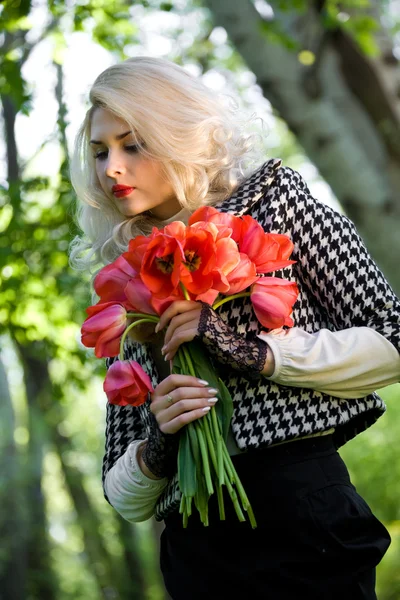 Blondýnka s červenými tulipány — Stock fotografie