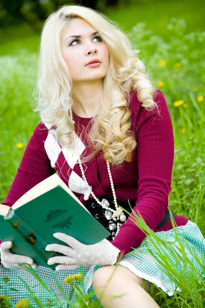 Mooie jonge blond met boek in zomer park — Stockfoto