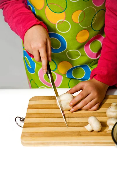 Девушка в фартуке, режет грибы — стоковое фото
