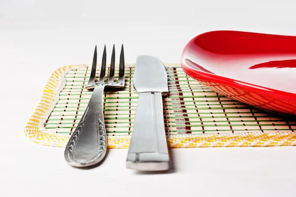 Piastra rossa, coltello e forchetta isolati su bianco Foto Stock