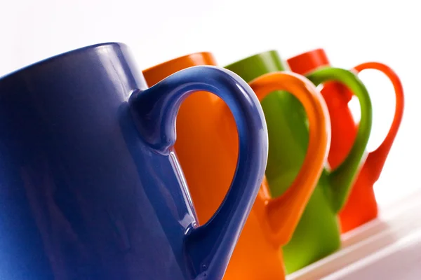 Multicolored ceramic mugs over white Royalty Free Stock Photos