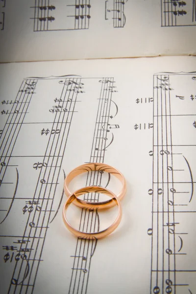 Wedding rings on the notes.music hearts — Stock Photo, Image
