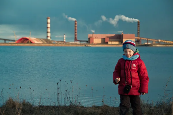 stock image A child on the shore of the lake near the mines. human impact on