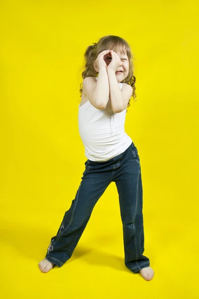 Fröhliches Mädchen tanzt auf gelbem Hintergrund — Stockfoto