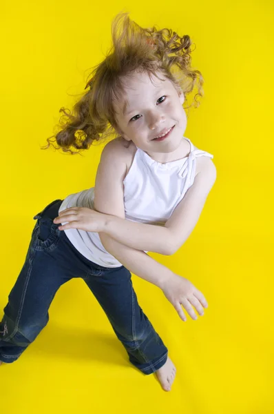 Chica alegre baila sobre un fondo amarillo —  Fotos de Stock