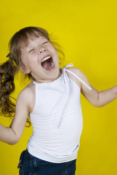 Menina alegre dança em um fundo amarelo — Fotografia de Stock