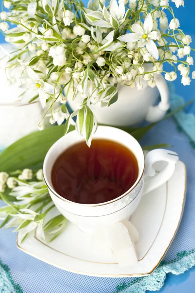 Chá em uma xícara e lírios do vale — Fotografia de Stock