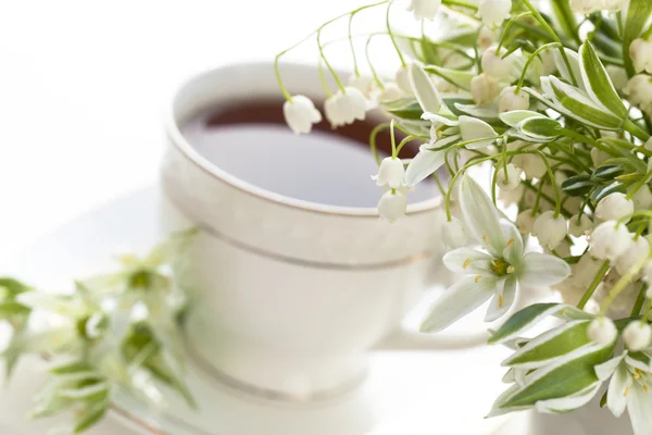 Te i en kopp och liljekonvaljer — Stockfoto