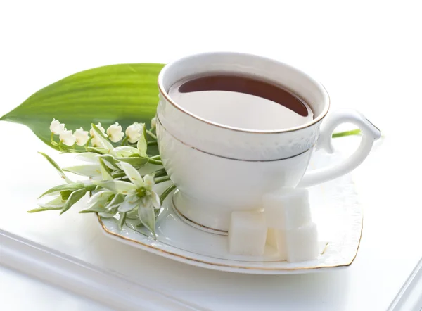 Tea in a cup and lilies of the valley — Stock Photo, Image