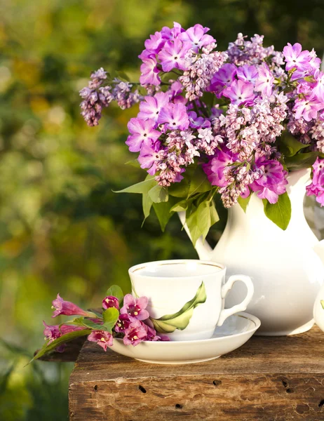 Porcelain cup with coffee and lilac — Stock Photo, Image