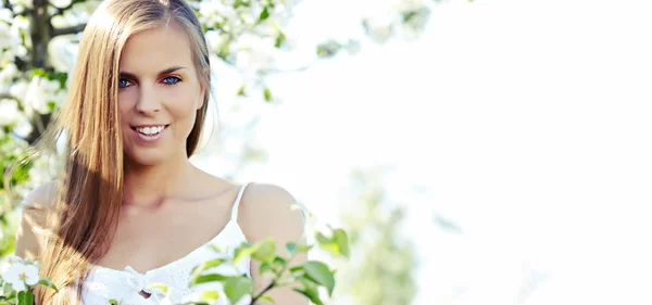 Portrait of young lovely woman in spring flowers — Stock Photo, Image