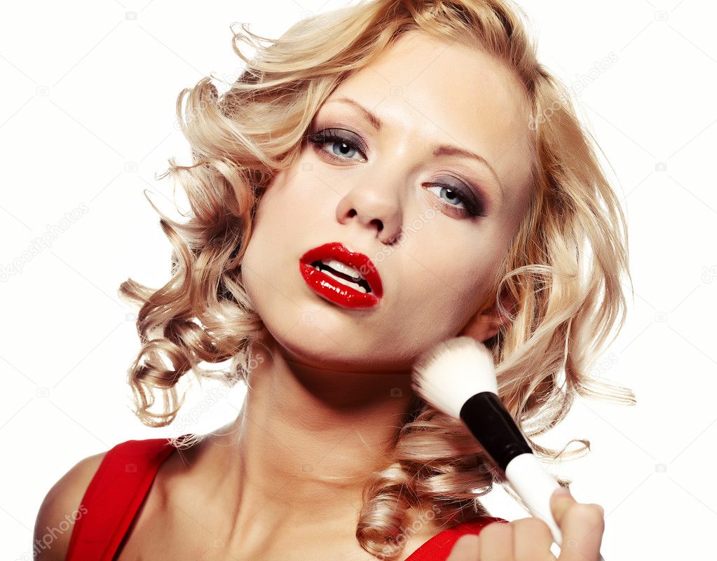 Beautiful blond woman applying makeup on her face