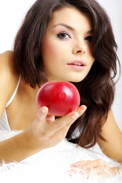 Ritratto di donna seduta sul letto e che mangia mela rossa fresca — Foto Stock