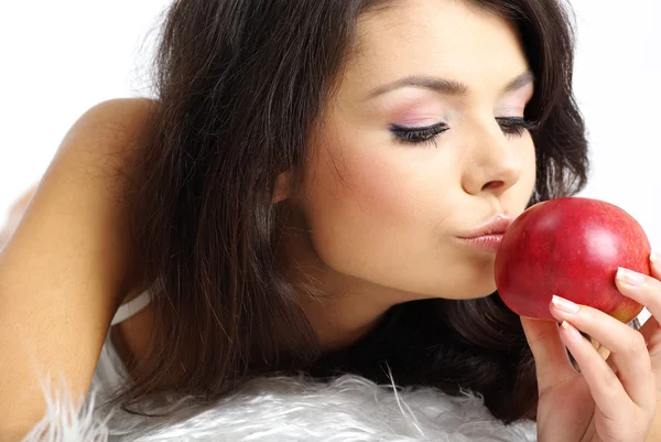 Yatakta oturmuş ve taze kırmızı elma yiyen bir kadın portresi — Stok fotoğraf